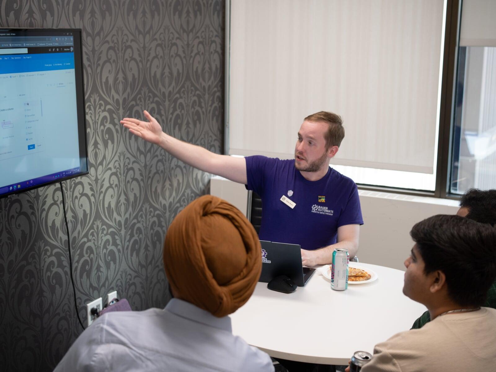 Ryley Bauer of Bauer Automate pointing at a screen presenting to clients